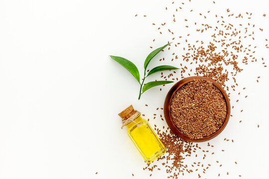Flax seeds in a spoon and bowl with a bottle of flaxseed oil