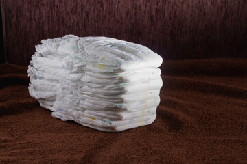 A stack of new baby diapers on a brown background