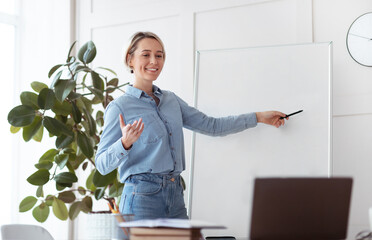 Online education. Young female tutor pointing at empty blackboard with space for design, giving web...