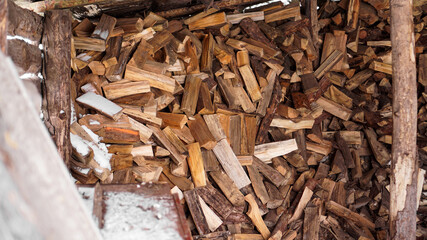 Logging in the village. Chopped logs under a canopy in winter. Natural wood background.