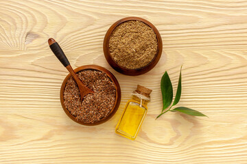 Flaxseeds in a spoon and bowl with a bottle of flaxseed oil and flaxseed flour