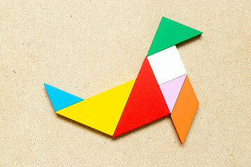 Color tangram puzzle in seal or sea lion shape on wood background