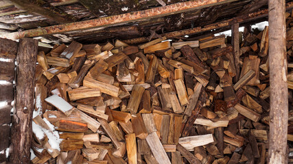 Logging in the village. Chopped logs under a canopy in winter. Natural wood background.