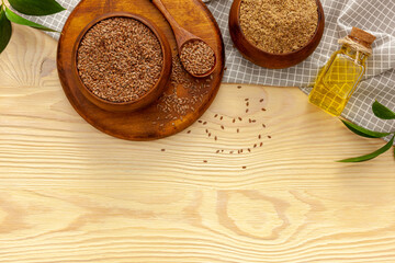 Flaxseeds in a spoon and bowl with a bottle of flaxseed oil and flaxseed flour