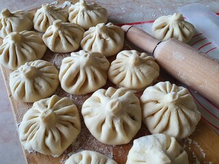 Homemade khinkali - Georgian dumplings, placed on the kitchen cutting board near the rolling pin.