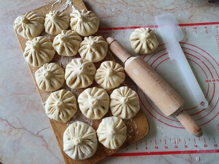 Homemade khinkali - Georgian dumplings, placed on the kitchen cutting board near the rolling pin.
