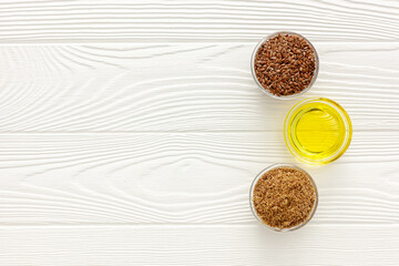 Flaxseeds in a spoon and bowl with a bottle of flaxseed oil and flaxseed flour