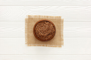Flax seeds in a spoon and bowl with a bottle of flaxseed oil