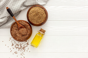 Flaxseeds in a spoon and bowl with a bottle of flaxseed oil and flaxseed flour