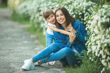 Attractive young mother holding her little daughter. Girls outdoors having fun together.