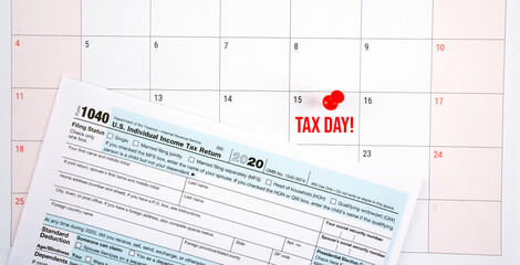 us individual income tax return 1040 form for 2020 with tax day text on april 2021 calendar. Panorama format.