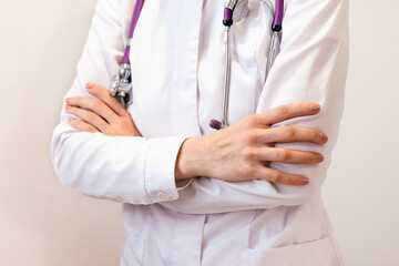 Doctor in uniform stands with her arms folded under her chest.Faceless,close-up,medical concept