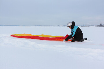 Man training with a kite on a frozen river in the winter, Kama Reservoir, Perm city, Russia
