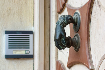 Antique door knocker contrasts with modern intercom.