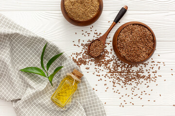 Flaxseeds in a spoon and bowl with a bottle of flaxseed oil and flaxseed flour