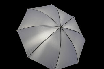 White silver reflective photo umbrella on a black background as an illustration or art design element. Reflective photo umbrella for flash in studio photography