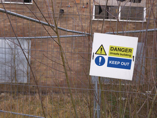 Danger sign outside derelict urban building after fire