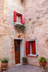 Fototapeta na wymiar Balconi rossi con porta e muratura in sasso e mattoni faccia vista in rosa anticato