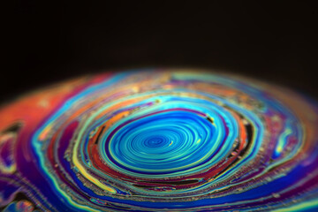 Macro picture of half soap bubble on black ground look like abstract psychedelic color planet in...