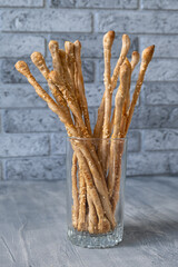 Bread sticks, italian grassini, homemade snacks with sesame seeds and whole grain flour in high glass. Vertical orientation.