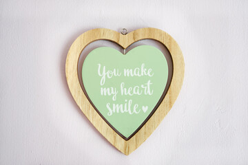 Top view of a wooden heart shape frame with the text " You make my heart smile"