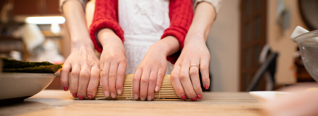 巻き寿司を作る親子の手元 © hakase420