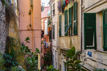 Vernazza, Italy - october 2020: Walking narrow streets of Vernazza village in Cinque Terre on the Italian Riviera. Everyday routine: woman hangs clothes on the balcony