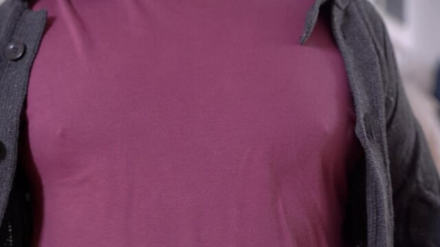 Fat man tries to button on jacket, but can not even reach edges to each other, close up. Silly guy washed his woolen cardigan in hot water and it shrank.