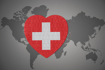 puzzle heart with the national flag of switzerland on a world map background.