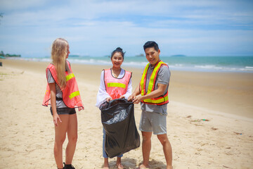 Group of volunteer picking trash into plastic bag for cleaning the beach in morning time. Volunteer concept.