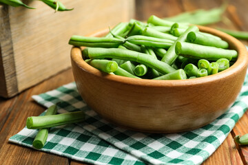 Fresh green beans in bowl on wooden table, closeup