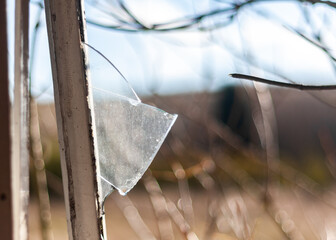 Broken glass following burglary in open window with metal frame sharp edge shard of glass sticking...