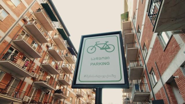 20th January, 2021 - Saburtalo, Tbilisi, Georgia: Post board sign with "Parking" in english and georgian with block house balconies in neighborhood.Concept of safety and ecological transportation in b