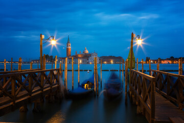 Gondolas anchored on Grand Canal in Venice, Italy. Long exposure night shot with motion blurred gondolas