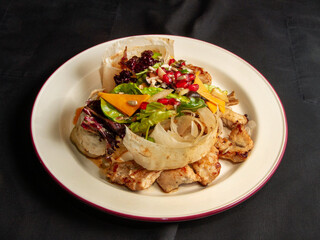 Salad with pieces of chicken breast, lettuce, cheese, garnished with pomegranate seeds