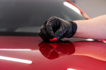 The master removes small dirt pieces from the car bonnet surface with special clay before...