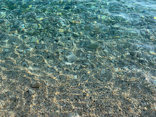 Transparent sea water texture, sea pebbles beach, water ripples