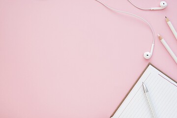 Feminine pink desk mockup, flat lay with notebooks, earphones, pen, soft pink background, space for...