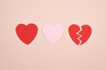 Paper hearts over the pink pastel background. Abstract background with paper cut shapes. Broken heart love relationship concept