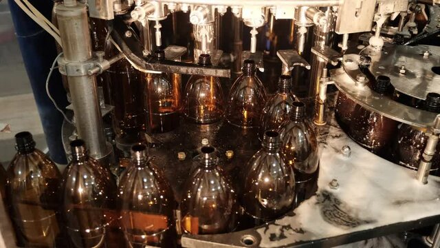 Row of brown plastic bottles for tasty beer drink transported by automatic equipment in brewery workshop closeup timelapse