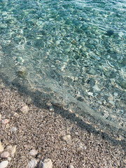 Transparent sea water texture, sea pebbles beach, water ripples