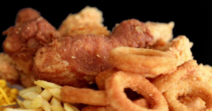 Macro view of Tasty french fries and crispy chicken nuggets with mustard and ketchup at black background