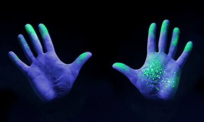 Human hands glowing from UV ultra violet light showing bacteria and viruses on a black background,...