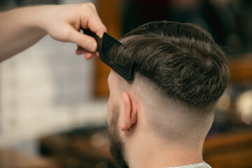 Fresh style. Close up of client of master barber, stylist during getting care and new look of hairstyle. Professional occupation, male beauty and self-care concept. Soft colors and focus, vintage.