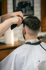 Fototapeta premium Fresh style. Close up of client of master barber, stylist during getting care and new look of hairstyle. Professional occupation, male beauty and self-care concept. Soft colors and focus, vintage.