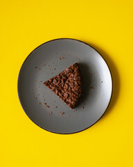 Brown cake on grey plate with yellow background