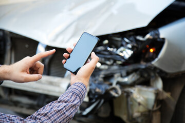 Man holds mockup mobile phone screen in hands after car accident. Calling insurance service in web...