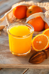 Glass of freshly sqeezed orange juice on a wooden table. Natural source of vitamins, healthy beverage for ideal breakfast. Bright sunny summer day. Close up, copy space for text.