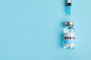 Filling syringe with coronavirus vaccine on light blue  background, flat lay. Space for text
