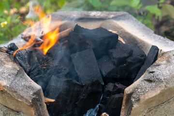 Burning black charcoal in the old stove with paper and dry wood. It produces a lot of smoke when it burns.